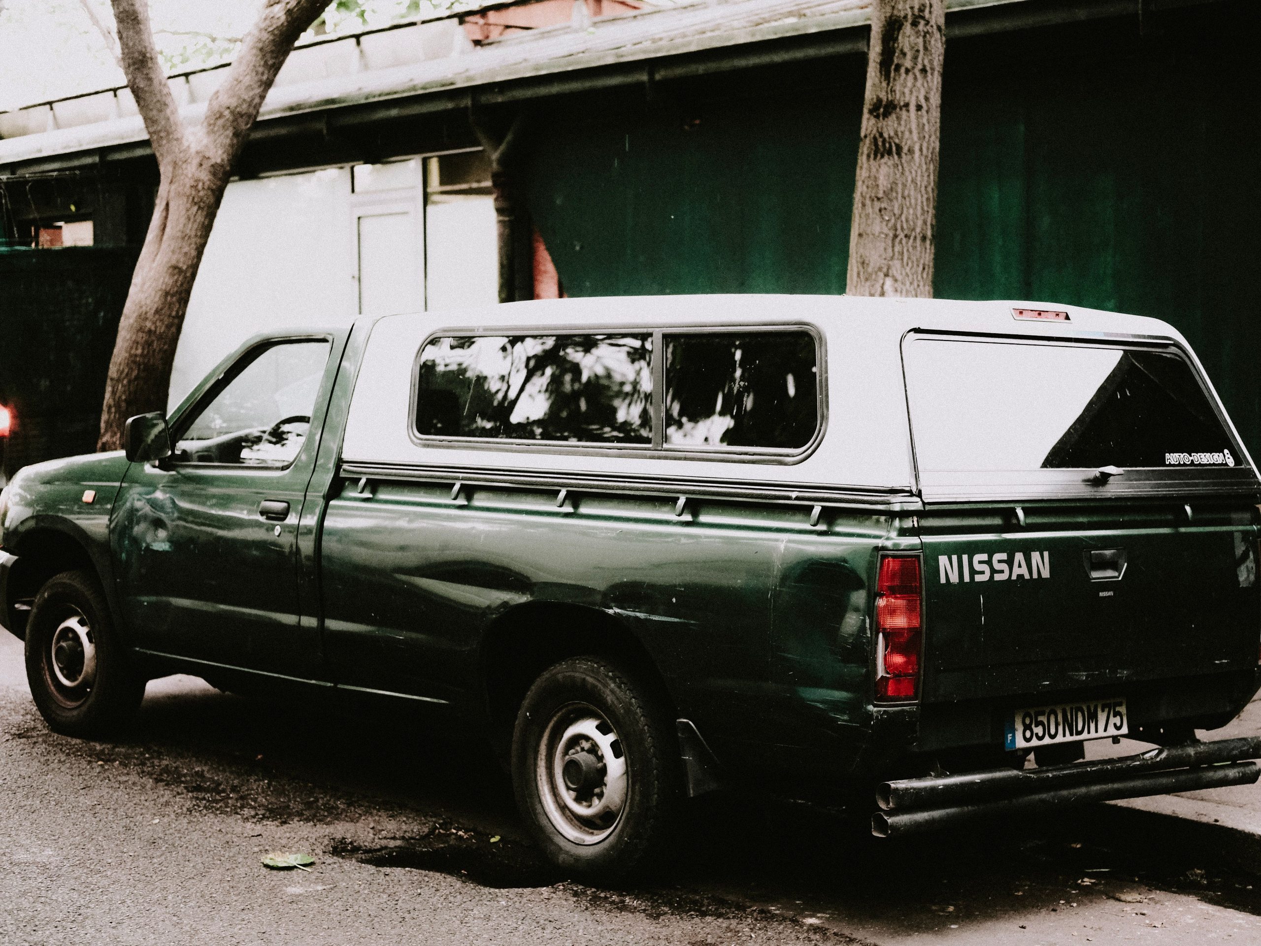 Green Nissan pickup parked on an urban street, showing its rugged body and stance.